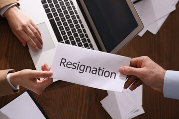 Employee giving resignation letter to boss in office, top view