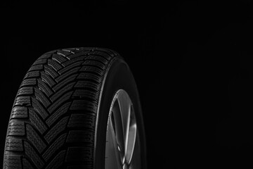 Fototapeta na wymiar Wheel with winter tire on black background, closeup. Space for text