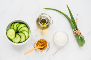 Homemade skin care concept. Green natural ingredients aloe vera, lemon, yogurt, turmeric, cucumber for making a cosmetic mask on a light background.
