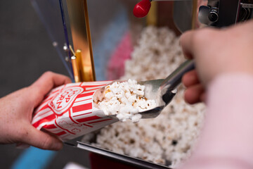 Scooping popcorn into a bag from a popcorn machine - obrazy, fototapety, plakaty