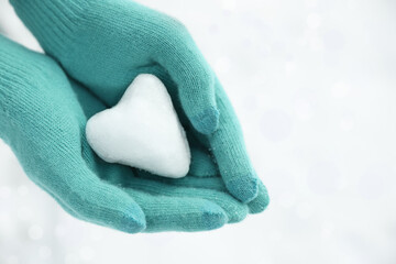 Woman holding heart shaped snowball in hands, closeup