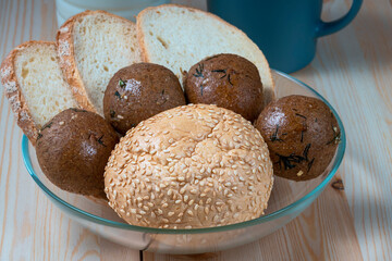 fresh delicious buns and slices of wheat bread on wooden kitchen table