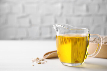 Sunflower seeds and oil on white table. Space for text