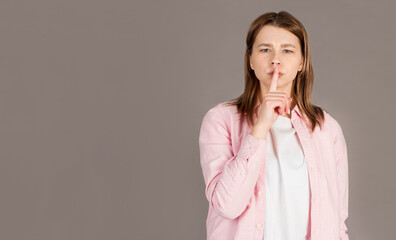 Portrait of brown-haired gorgeous attractive nice cute funny smililng young lady showing shhh taboo...