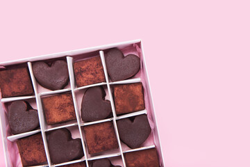 Box with chocolate heart shaped sweets on pink background. Valentine Day concept. Copy space.