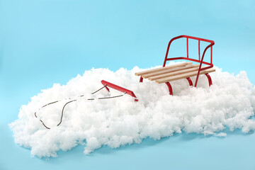 Empty sleigh in artificial snow on light blue background. Winter activity