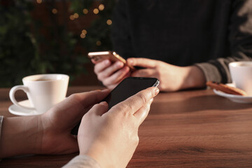 Women using mobile phones at table in cafe, closeup