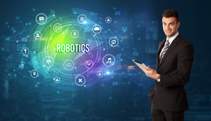 Businessman thinking in front of technology related icons and ROBOTICS inscription, modern technology concept