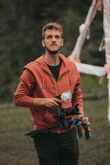 Shallow focus of a professional male photographer holding a camera and standing in a garden