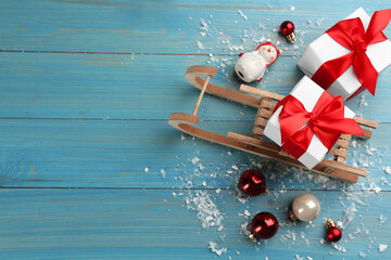 Beautiful Christmas composition with miniature sleigh on light blue wooden table, flat lay. Space for text