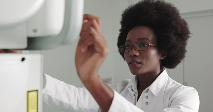 Portrait of Professional Doctor African Ethnicity Smiling At Camera. In the Hospital, Female Technician adjusts X-Ray Scanner Machine. Modern Hospital with Technologically Advanced Medical Equipment