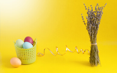 painted eggs in a basket lie on a yellow table. preparing for Easter