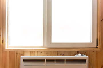 Plastic window installed in a country house, under the window there is an electric heating radiator