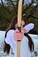 Young girl aims forward with a bow and arrow
