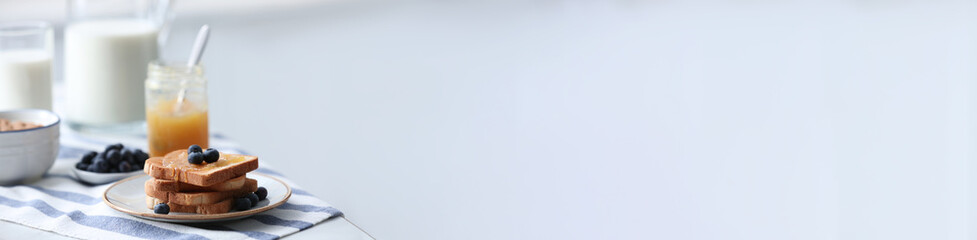 Toasted bread with jam and fresh blueberries on table in kitchen