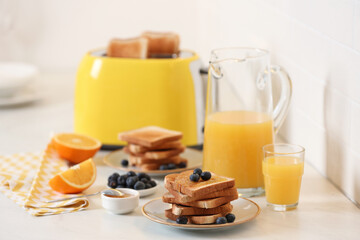 Toasted bread with jam and fresh blueberries on white table in kitchen