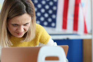 Woman works on computer in background hanging an American flag