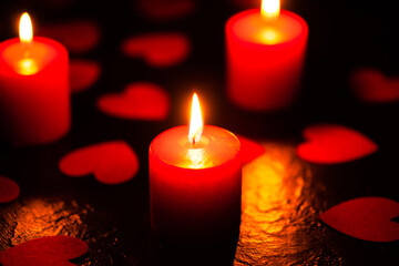 Three red burning candles. Candles with hearts. The background for the greeting card. A greeting card for Valentine's Day. February 14 is valentine's day. Used as a background or texture, soft focus
