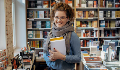 Young woman reading book. Young female student reading book at book store. - obrazy, fototapety, plakaty