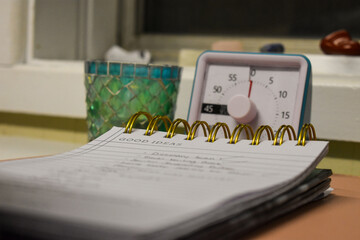 Close up of a notepad, timer and candle on desk