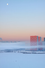 Residential building in fog amid dawn. Winter landscape in Russia