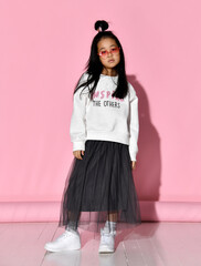 Portrait of a stylish Korean girl in a white sweater, tulle skirt, sneakers and red heart-shaped...
