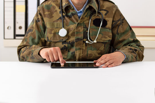 Cropped shot of a army doctor using a digital tablet in hospital office.