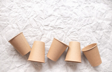 disposable kraft paper cups laid out on gray crumpled paper