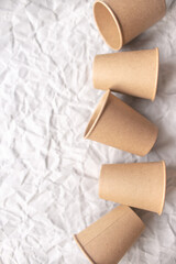 disposable kraft paper cups laid out on gray crumpled paper