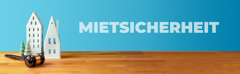 Mietsicherheit. Richterhammer, Häuser und Bäume auf Tisch in Anwaltskanzlei. Text auf blauem...