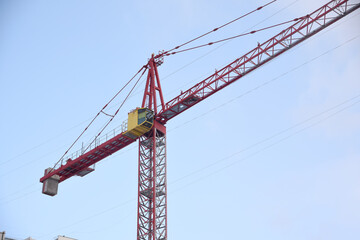 Construction crane with yellow booth on sky background