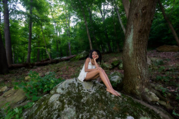 Naklejka premium Woman at lake on swing, large boulder, and in water