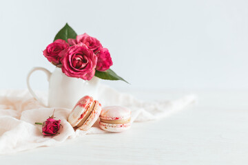 Tasty french macaroons with pink roses on a white background.