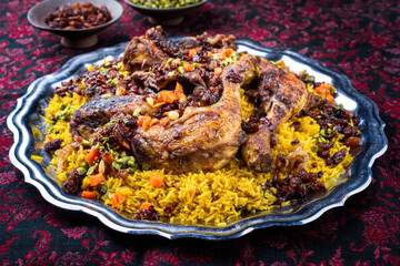 Traditional fried Arabic chicken majboos with chicken leg and jeweled rice served as close-up in a rustic oriental tray