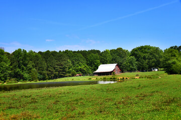 Fototapeta na wymiar Barn With Pond in Large Field