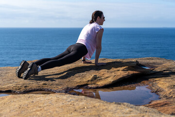 Fototapeta na wymiar Young Woman lady Practicing Yoga on a cliff overlooking the ocean at Sunrise, Healthy Lifestyle 