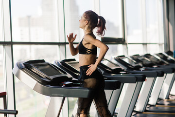 A young and beautiful female trains with a barbell in the gym. Posing with elements for training