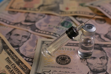 Syringe vial with vaccine on the background of American dollars