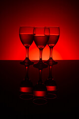 Filled wine glasses with red background