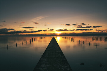 Long wooden jetty over sea with sunset on the Swedish west coast.