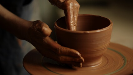 Girl shaping clay product in pottery. Woman sculpting clay pot in workshop