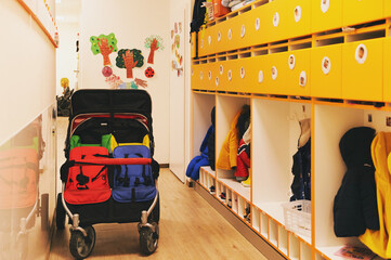 Empty hallway with hangers in day care or kindergarten, double stroller for outside walk