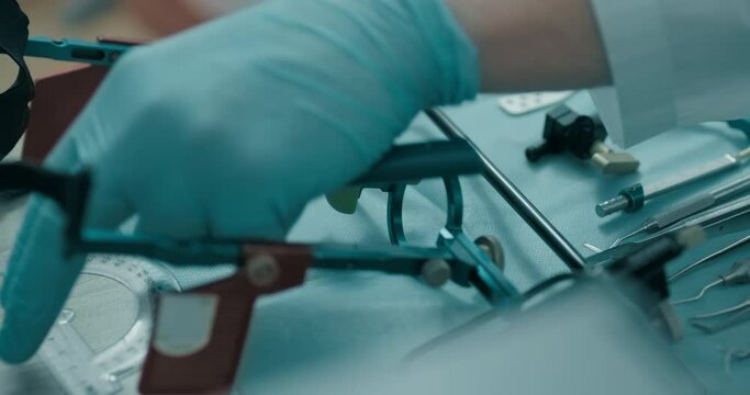 There are dental tools including a mouth mirror, dental tweezers, a dental probe, a dental scaler, axiograph lying on a table on a tissue, a pen and a protractor are being taken by dentist.