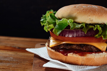 Delicious burger with lettuce, tomato and red onion and bacon on homemade bread with seeds and...