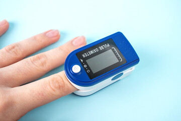 Pulse oximeter to measure pulse rate and oxygen levels isolated on blue background. Medical concept. Diagnosing coronavirus.