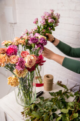Florist's workplace. Tools and flowers before starting work on the table against the background of a white brick wall. A florist chooses a flower for a bouquet. Tutorial. Step by step