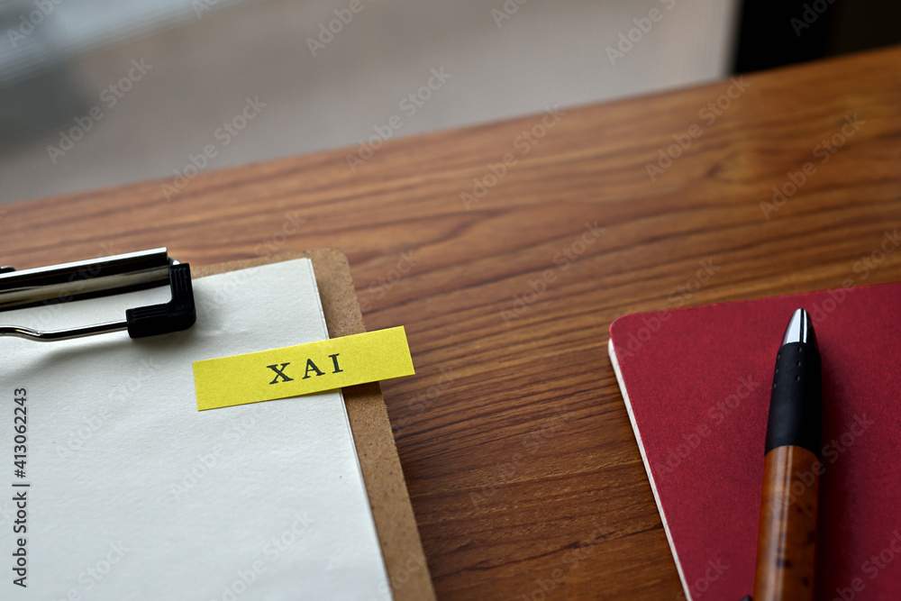 Aufkleber there is a notebook, a pen, and a clipboard with a sticky note stuck to it that says xai written on 