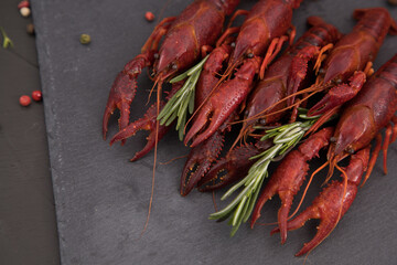 Delicious boiled crayfish close-up on a stone plate with pepper, lemon and parsley. free space for your text. Black background.