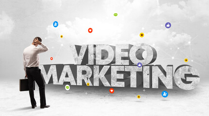 Young businessman standing in front of VIDEO MARKETING inscription, social media concept
