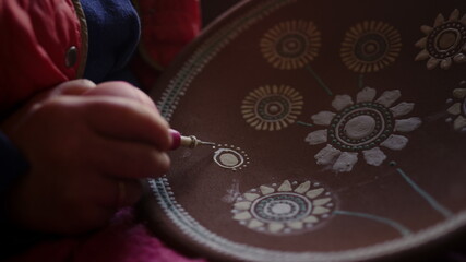 Artist making decoration on clay plate in studio. Woman making ornamental decor 